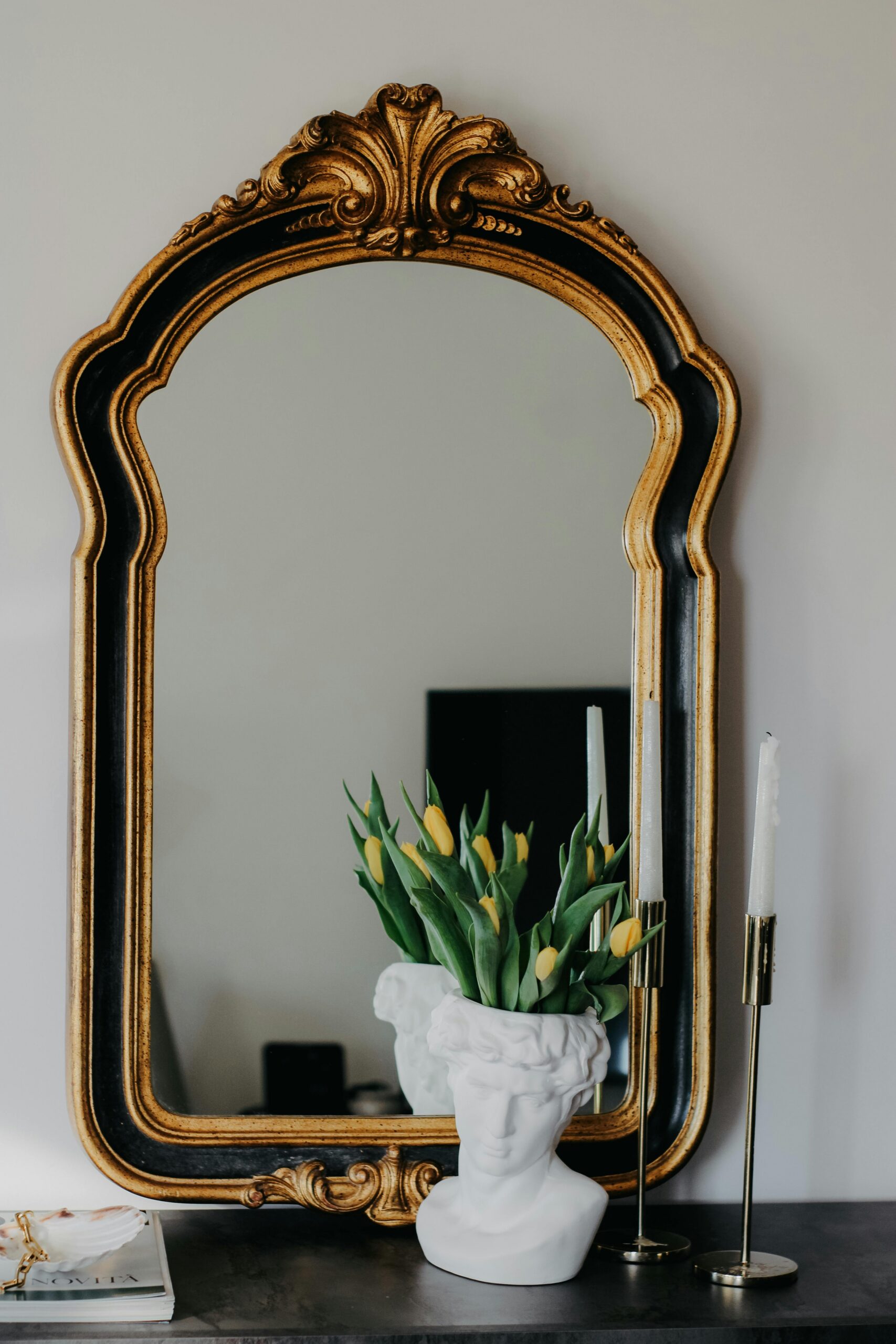 Bust vase with flowers and candles in front of mirror
